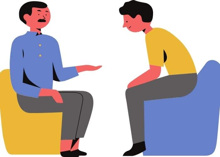 Two people having a conversation with one person talking and the other leaning in.