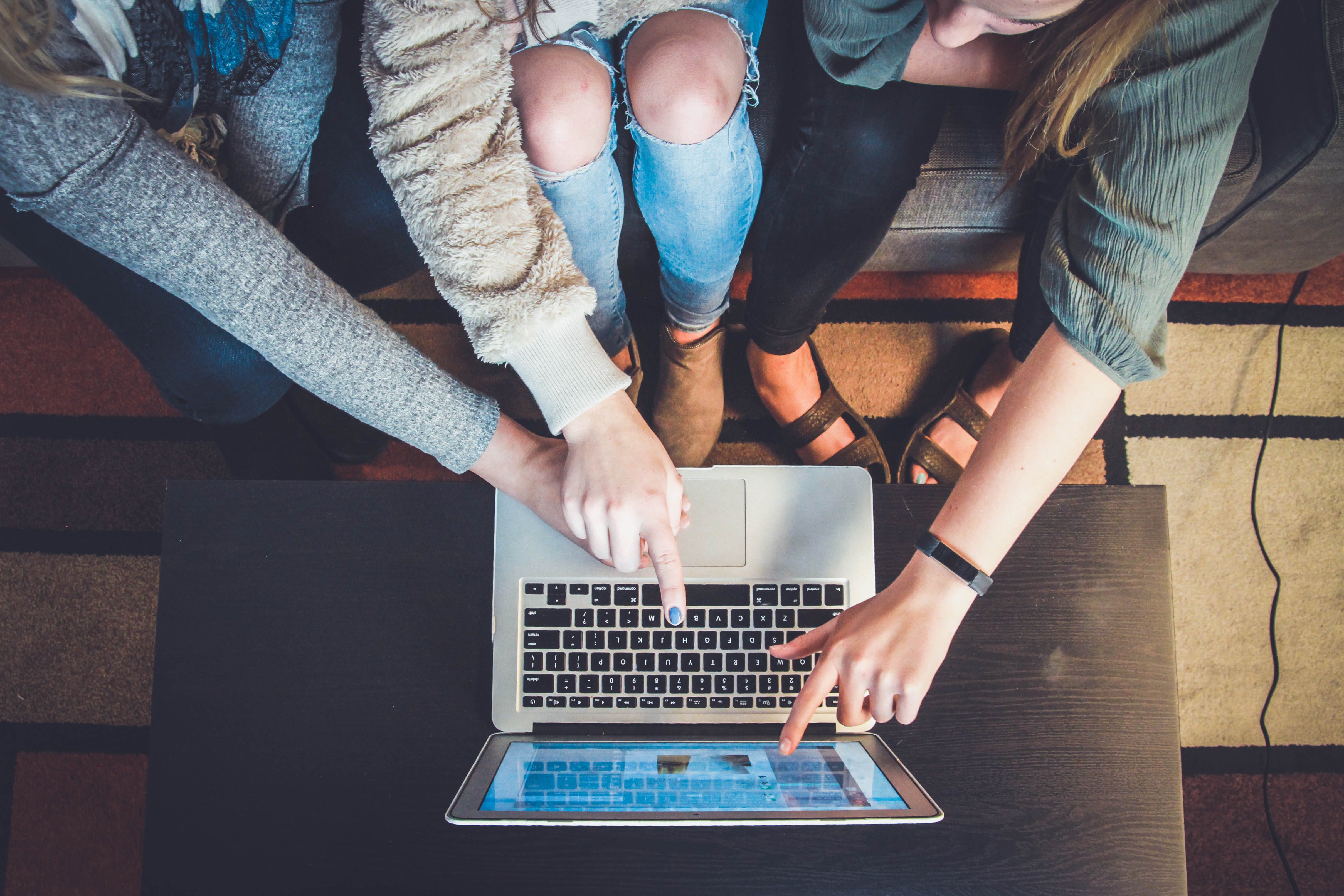Multiple people pointing at a laptop screen.
