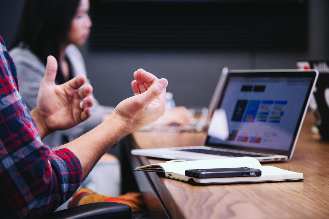 Person on laptop gesturing with his hands while talking showing the use of non verbal communication in the workplace.